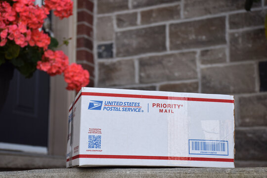 Closeup of United States Postal Service priority mail parcel box placed on the front porch of a residential house
