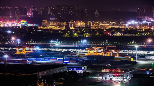 Night view of busy container port terminal with cranes and city lights in background