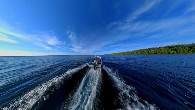 Man driving bass boat while woman seating at the front. Power sport, outboard fishing boat, with two people. Man and woman boating during fishing on the small v-hull boat.