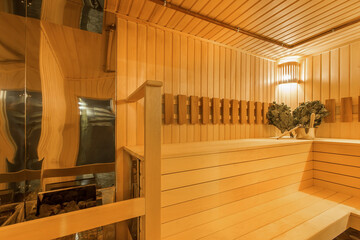 The interior of a traditional Finnish sauna made of light wood. Bath accessories, brooms.
