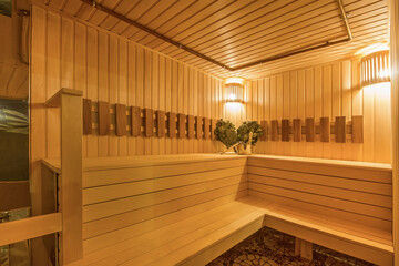Traditional Finnish sauna made of light wood. Soft lighting, bench and bath accessories.