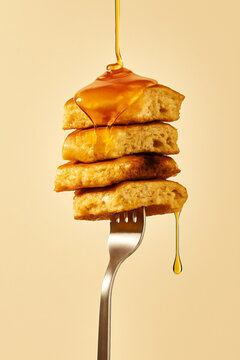 Stack of fluffy pancakes with dripping syrup on a fork, isolated background