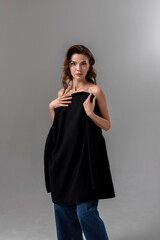 Fototapeta premium Portrait of a woman holding a black garment against a neutral gray background indoors