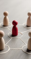 Vibrant red figure stands central to interconnected wooden peg people symbolizing teamwork and connection