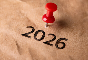 Red pin marks year 2026 on brown paper