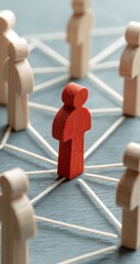 Red figure stands out connected to diverse wooden people in a network symbolizing teamwork and community bonds