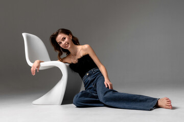 Model poses gracefully with a modern chair in a minimalist studio setting