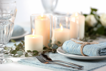 Elegant table setting with candles and blue linen creating a warm and inviting atmosphere for a special occasion perfect for wedding or event planning