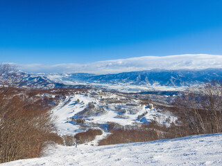 A vast snowy valley and hotel area seen from a high point at a ski resort (Madarao, Niigata, Japan)