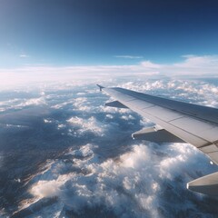 Obraz premium View from airplane window showing wing over clouds and blue sky during daytime flight