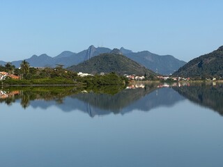 Lagoa de Piratininga em dia de céu azul com agua espelhando as montanhas 