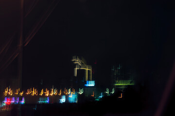 A beautiful shot of a distant city skyline at night, with glowing lights reflecting on the water.