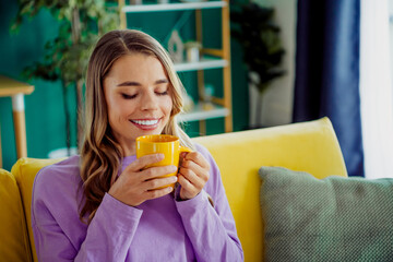 Happy young woman enjoying a peaceful moment at home with coffee in a cozy modern living space