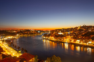 picturesque scene of Porto at dusk, featuring glowing city lights, the prominent bridge over the douro river
