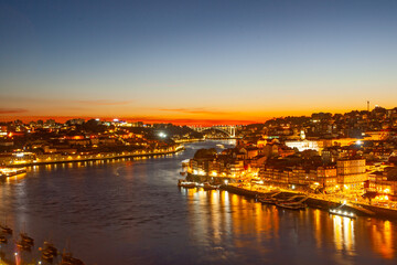 picturesque scene of Porto at dusk, featuring glowing city lights, the prominent bridge over the douro river