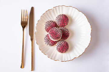 
Sweet raspberry and vanilla macaroons with leopard design on plate