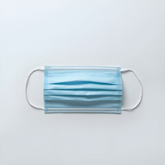 A single, blue surgical mask rests centered on a plain white background.