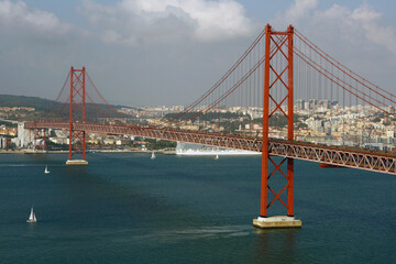 Red Suspension Bridge Over Lisbon River With City Skyline and Boats