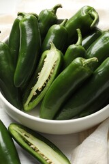 Fresh jalapeno peppers in bowl on white table, closeup