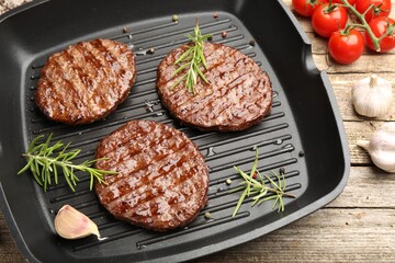 Pan with grilled patties, tomatoes and spices on wooden table, above view