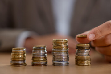 Woman counting coins at wooden table indoors, selective focus