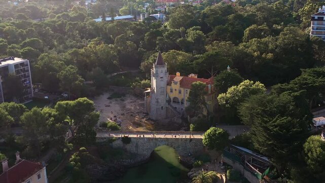 Aerial drone tilt-up shot of Museu Condes de Castro Guimaraes surrounded by lush vegetation in Cascais city, Portugal, showcasing the historic building and greenery