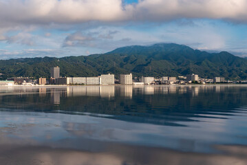 早朝の琵琶湖　静かな湖面に湖西のマンション群と背景の比叡山が映る風景　滋賀県大津市