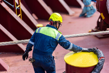 Fototapeta premium A deck crew member at the forward mooring station of large merchant ship, focused on securing the ship safely as she just moored in the port. 
