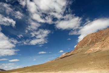 Vast desert landscape under a blue sky with scattered clouds