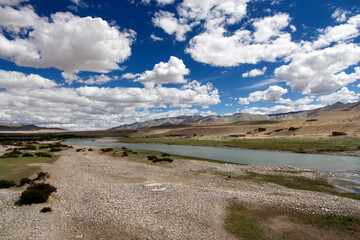 Vast river flowing through open arid landscape under cloudy sky