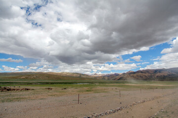 Vast open land with dramatic clouds and distant mountains