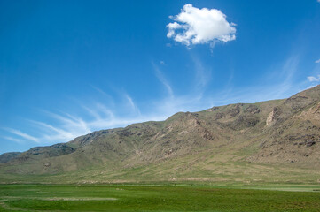 Vast mountain range under clear blue sky with scattered clouds