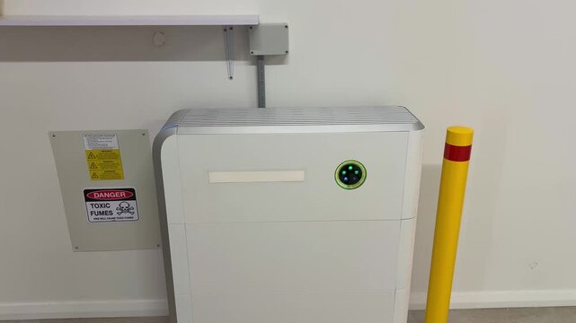 Solar battery charging in a home garage with white walls and safety sign