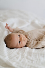 Cute baby lying on a soft white blanket with a calm expression while raising arms. Beautiful...