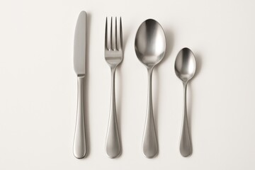 Polished stainless cutlery set arranged neatly isolated on pure white with soft shadow