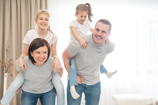 Mother And Father Giving daughters Piggyback in living room