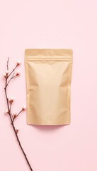 A Minimalist Arrangement Featuring a Blank Kraft Paper Pouch and Delicate Blossoms on a Pastel Pink Surface