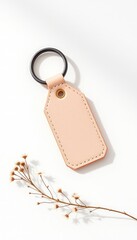 Neutral toned leather tag with a metal ring paired with a delicate dried floral accent against a clean, bright white backdrop