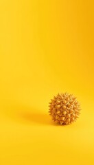 Spherical spiky object presented against a minimalist vivid yellow backdrop, offering space for text and design elements
