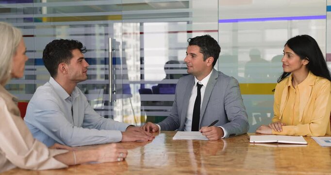 Two young multinational businessmen concluding agreement, shaking hands