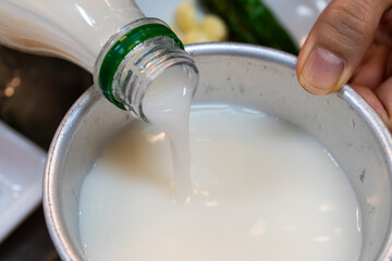 pouring makgeolli into the metal cup