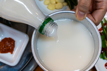 pouring makgeolli into the metal cup
