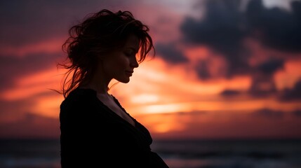 Fototapeta premium A woman s silhouette stands against a dramatic sunset over the ocean evoking peace and contemplation