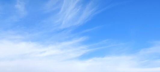 Bright blue sky with fluffy white clouds in summer. Sunny day with a clear blue sky view. Nature sky background with fluffy clouds.