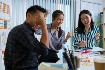 Obraz premium Three people are sitting at a table, working on a project. One of them is holding a piece of paper with a design on it. Scene is collaborative and focused 
