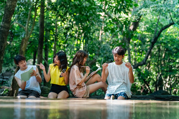 Happy young Asian man and woman travel nature mountain hiking and camping on summer holiday vacation. Generation z people friends enjoy and fun active lifestyle relaxing by waterfall lagoon together.