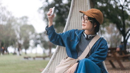 Asian woman gen z using smartphone selfie for social media at camping site solo travel freedom journey traveller