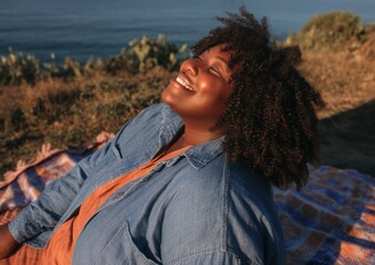 Authentic Black Woman Digital Detox Outdoors Smiling Relaxed at Seaside Retreat Premium Wellness Lifestyle Content for Mindful Marketing and Social Media