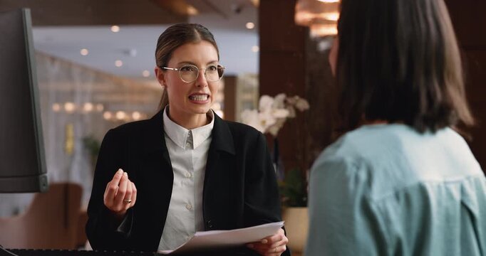 Receptionist talking with guest, holding papers with registration form
