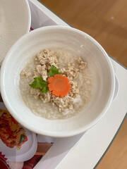 Boiled rice with pork chops, sprinkle with vegetables, pepper and deep fried garlic, in a white tile bowl, white background.